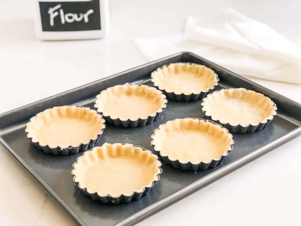 unbaked mini tarts on baking sheet