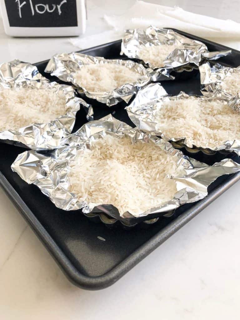 Mini tarts filled with rice on baking sheet