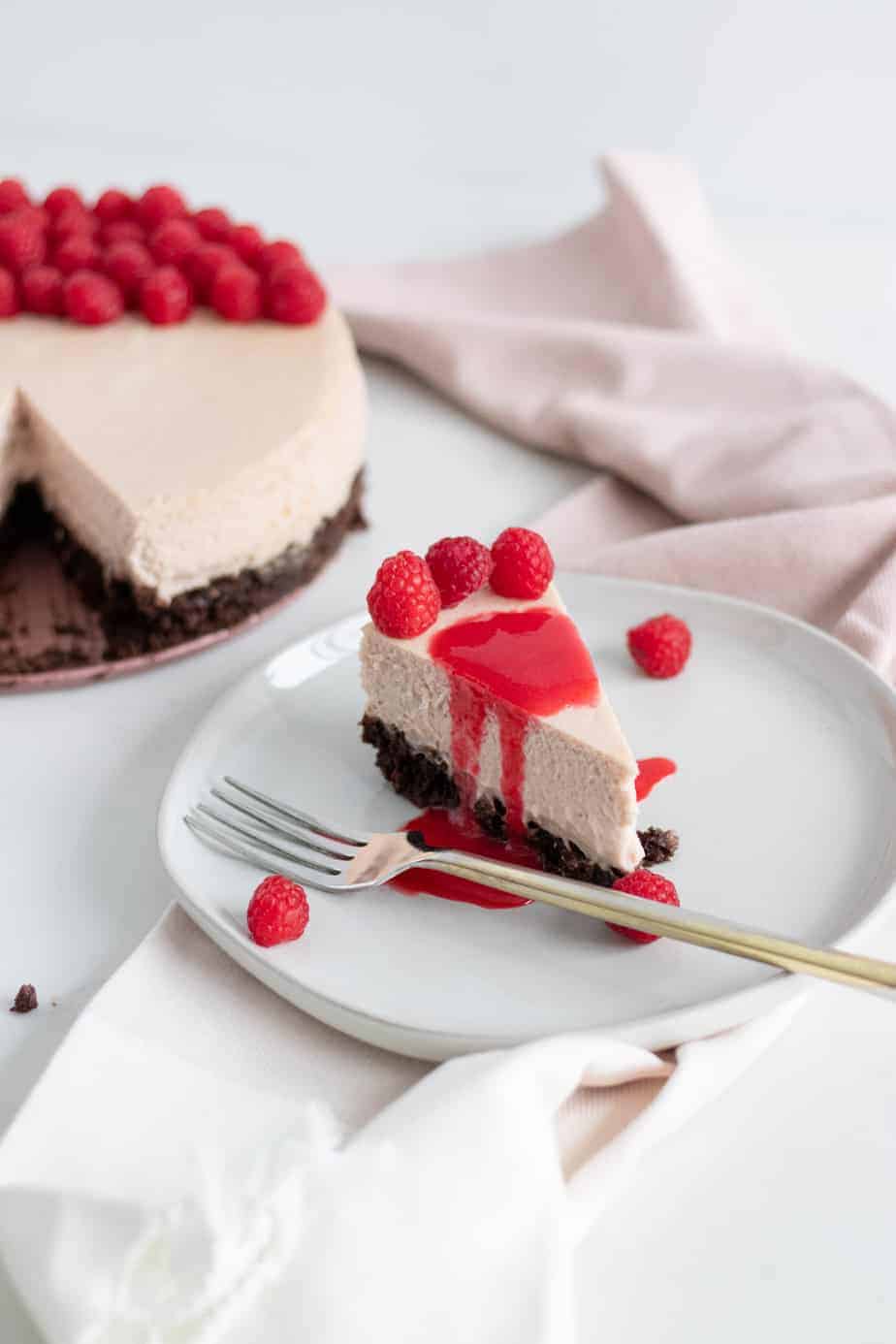 Raspberry brownie cheesecake with slice cut out on plate