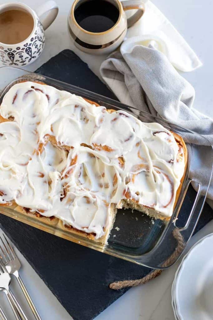 pan of apple cinnamon rolls with cups of coffee