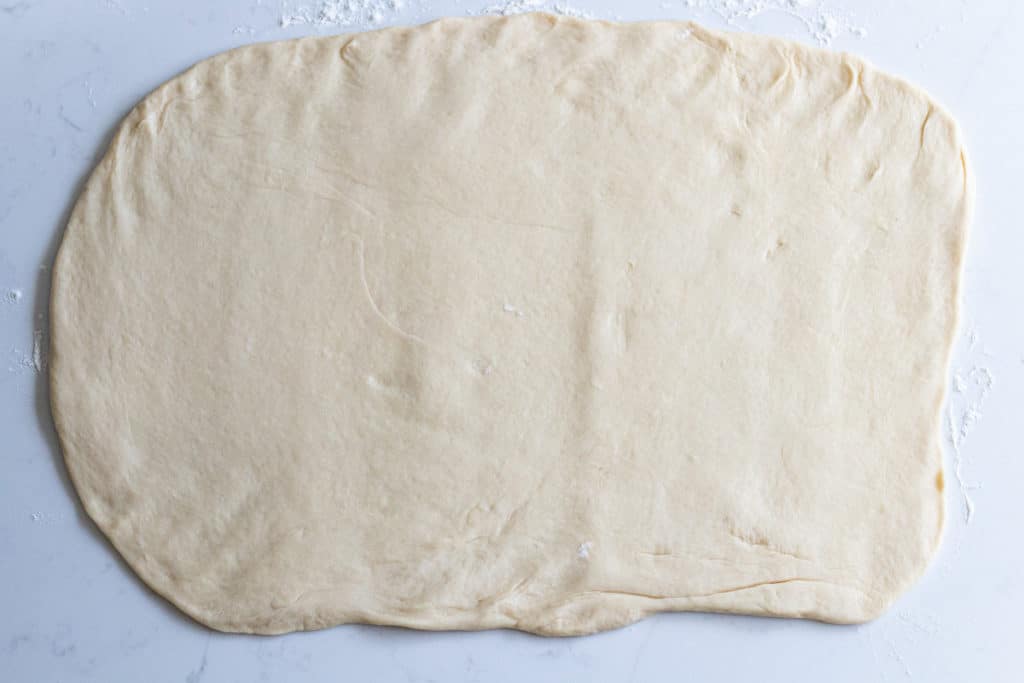 Cinnamon roll dough rolled into flat rectangle