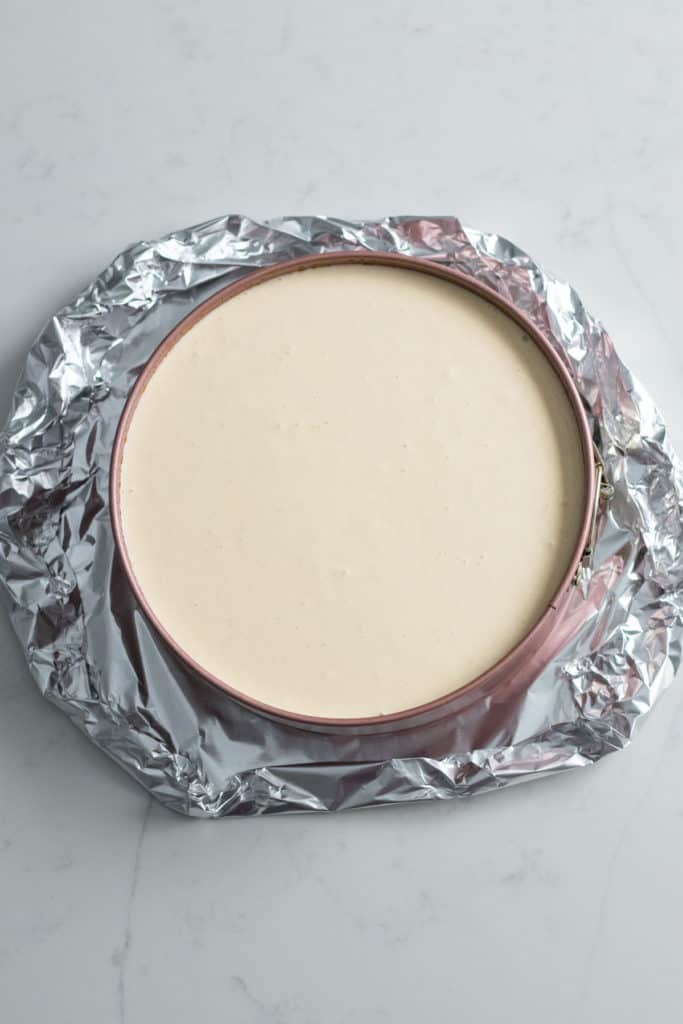 foil wrapped around pan of cheesecake batter