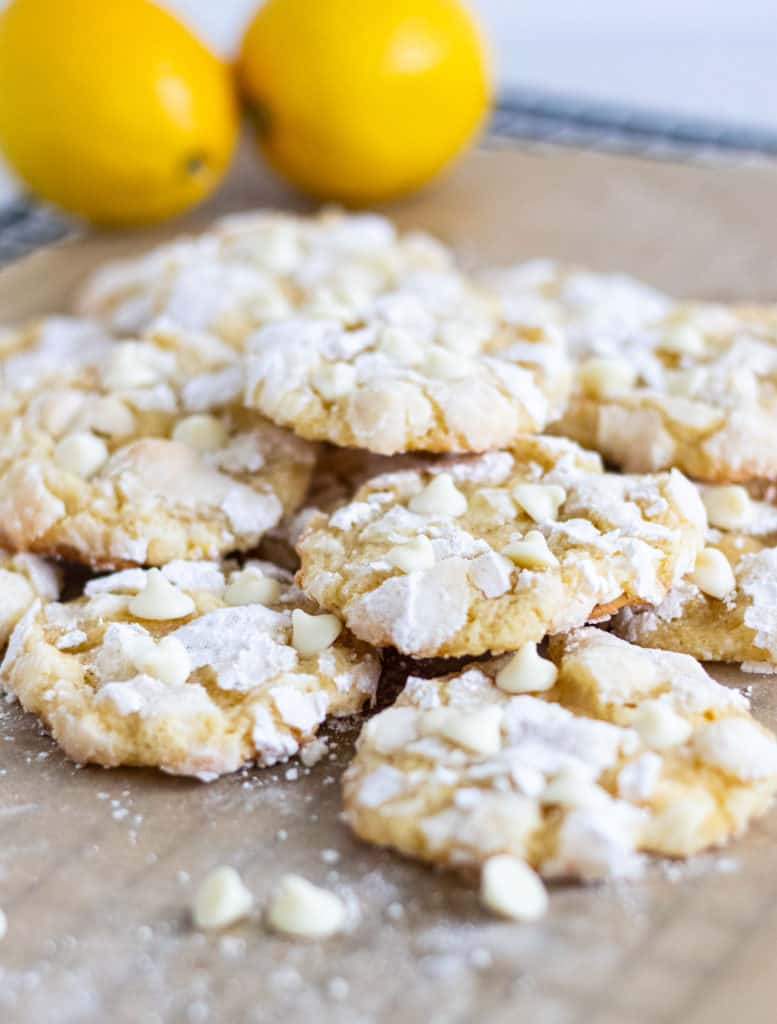 pile of lemon crinkle cookies with lemons in background