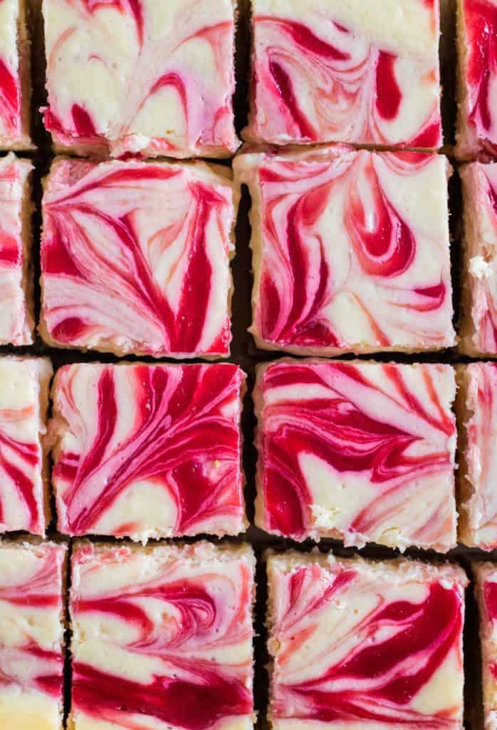 close up of raspberry swirled cheesecake bars cut into squares