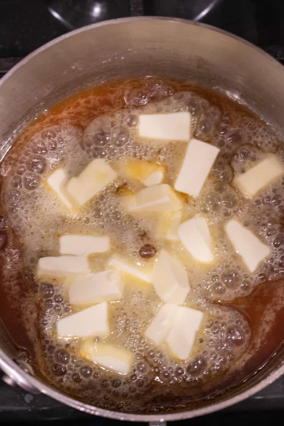 cubed butter in melted sugar in saucepan