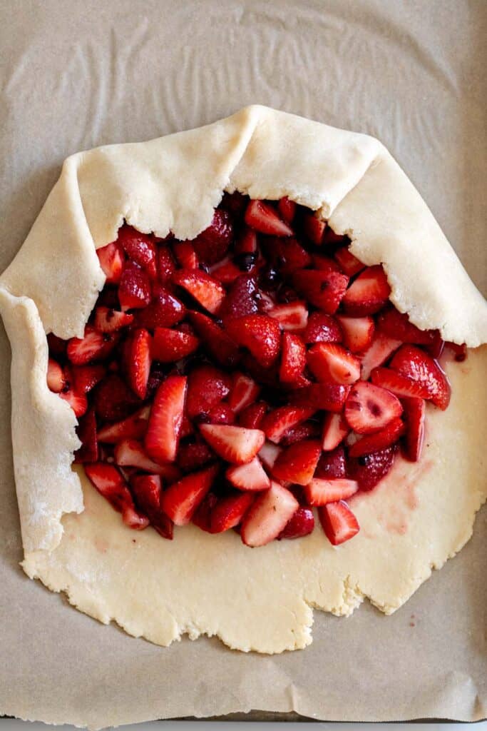 strawberries piled onto center of pie dough with edges folded up