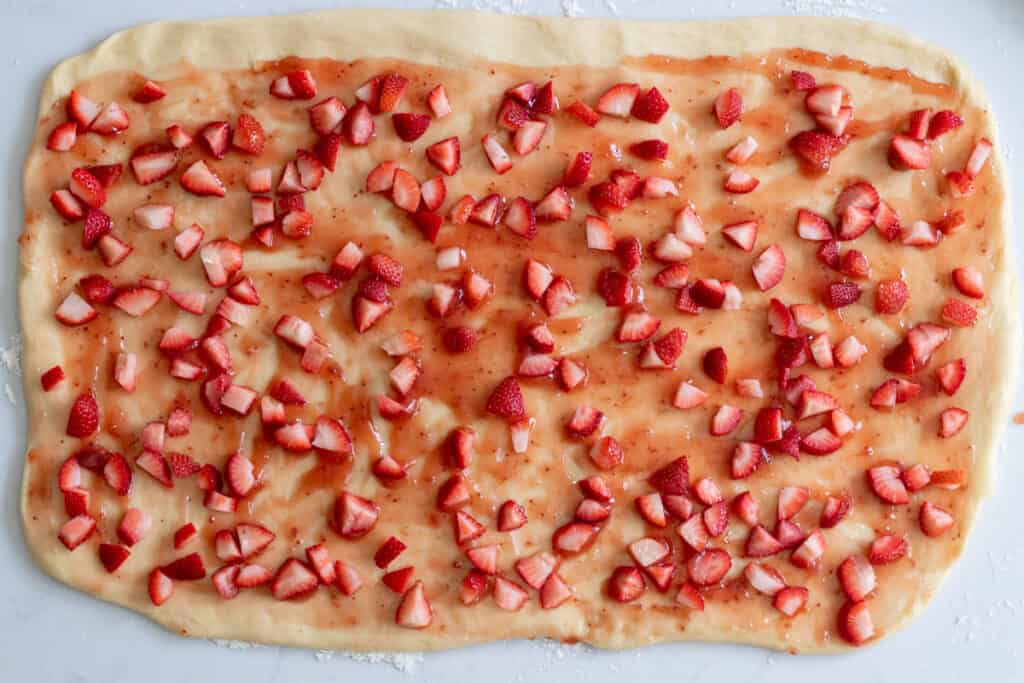 dough spread with strawberry preserves and chopped strawberries