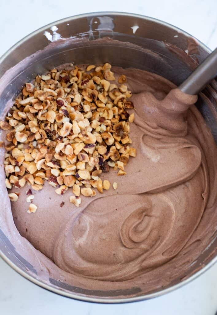 chocolate no-churn ice cream in a large mixing bowl with chopped hazelnuts on top