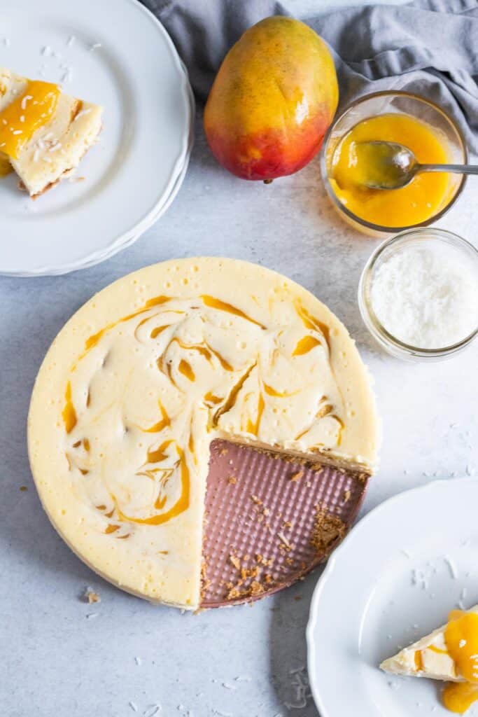 overhead view of mango cheesecake on pink plate with slices cut out