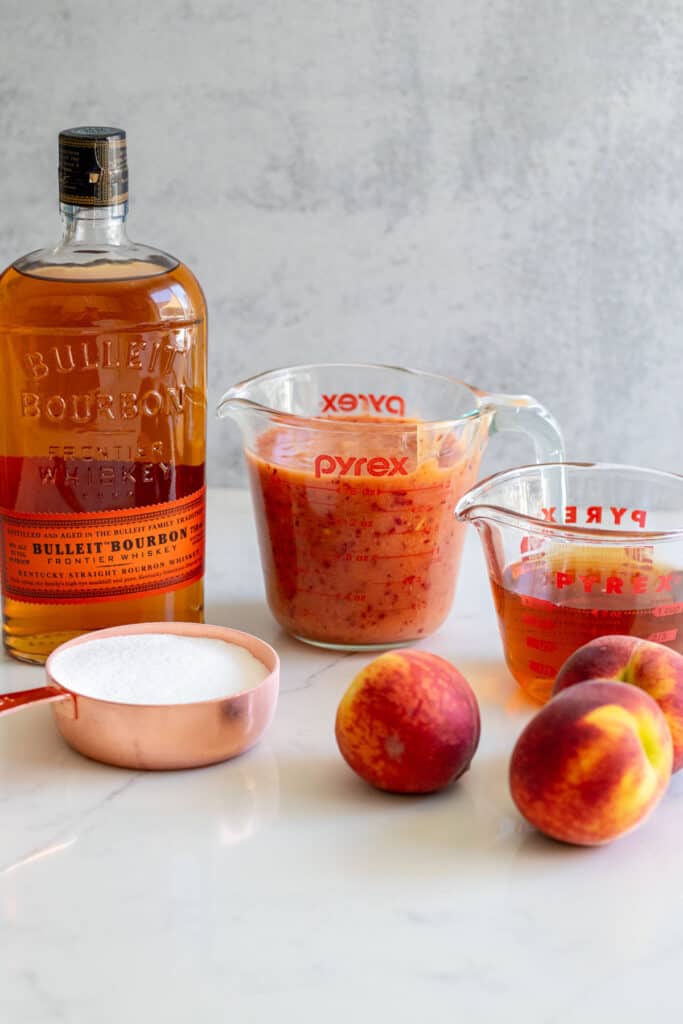 Bourbon, peach puree, peaches and sugar on counter