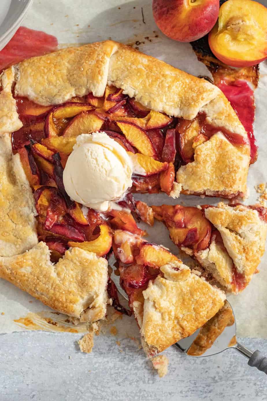 galette with peaches with 2 slices cut out and a scoop of vanilla ice cream on top