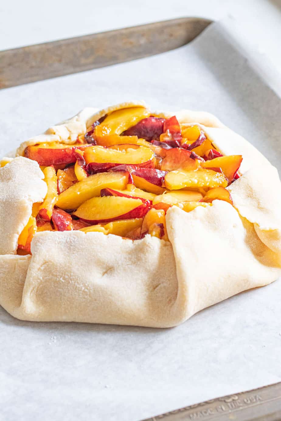 Uncooked peach galette on baking sheet