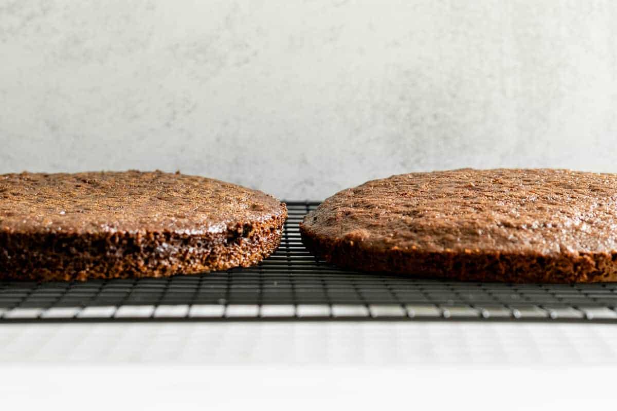 2 chocolate cake layers on a black wire cooling rack