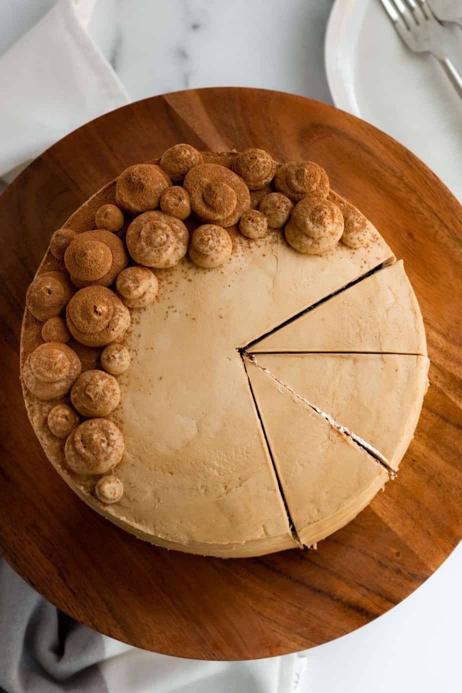 chocolate mocha cake on a wood cake stand with 3 slices cut from the cake