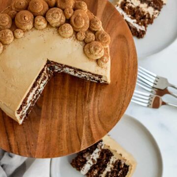 chocolate mocha cake on a wood cake stand with 2 slices of cake on plates