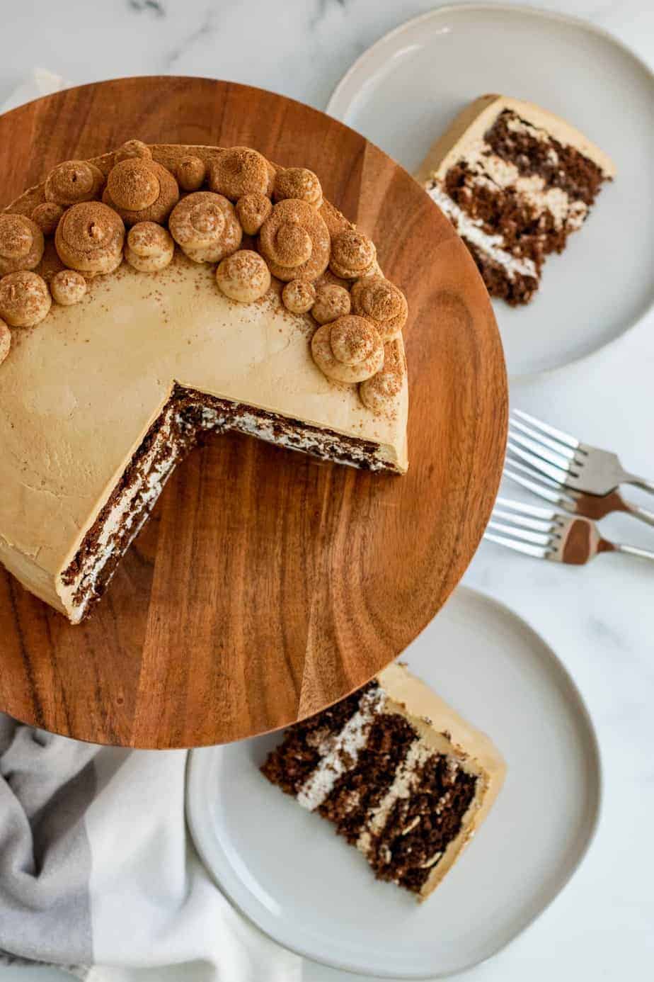 chocolate mocha cake on a wood cake stand with 2 slices of cake on plates 