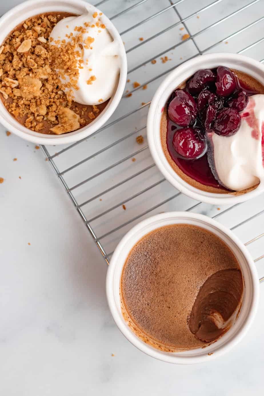 3 chocolate pots de creme on baking rack. One with bourbon cherries and one with peanut butter pretzel crumble.