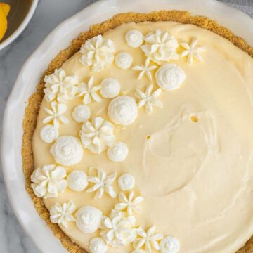 lemon cream pie in a white pie dish next to bowl of lemons