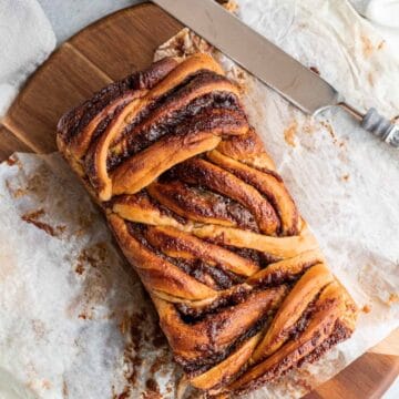 apple cinnamon babka on parchment paper on top of a round wood cutting board