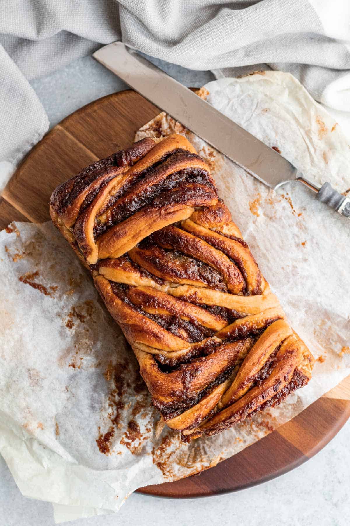 apple cinnamon babka on parchment paper on top of a round wood cutting board