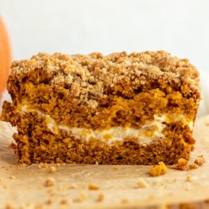 close up of loaf of pumpkin bread cut open showing cream cheese layer