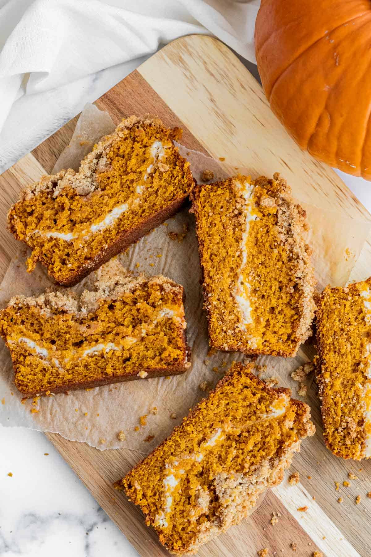 slices of pumpkin cream cheese bread laying on a wooden cutting board