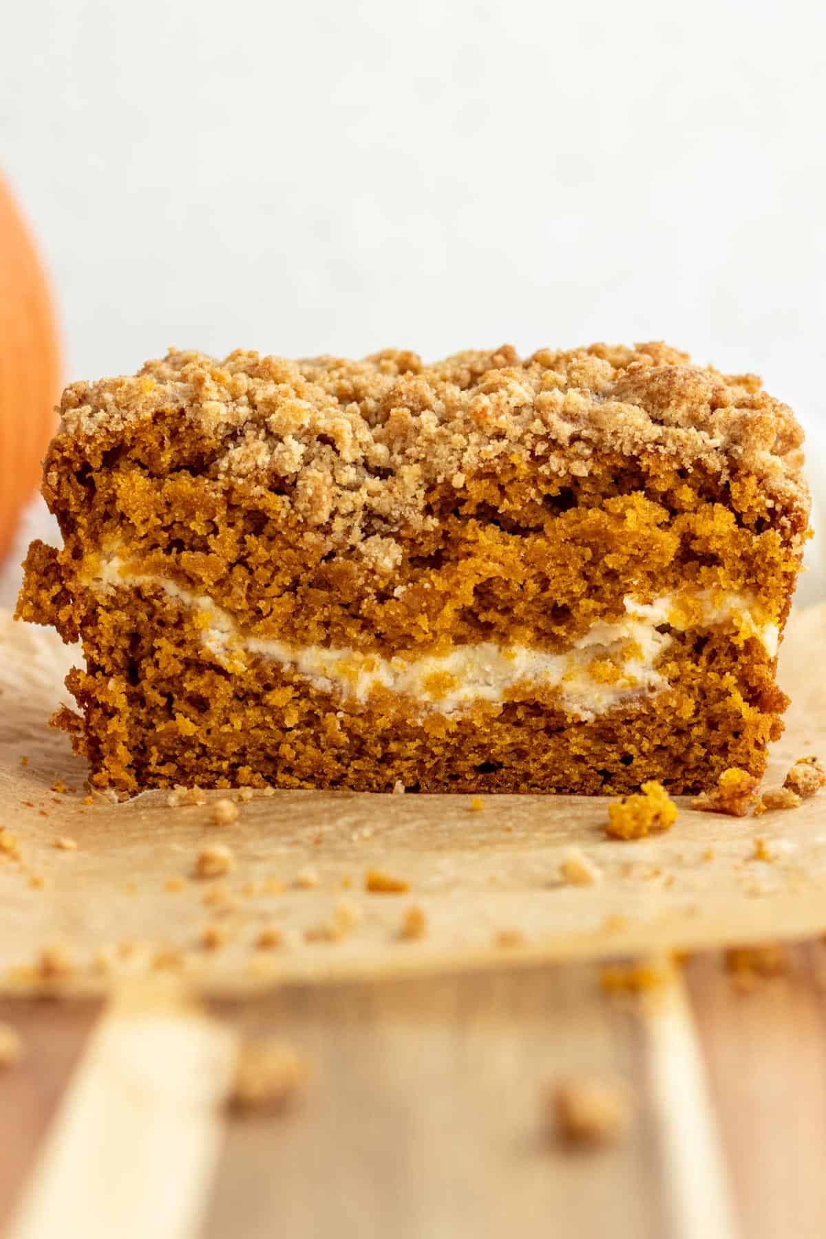 close up of a loaf of pumpkin cream cheese bread cut into showing layer of cream cheese in the bread