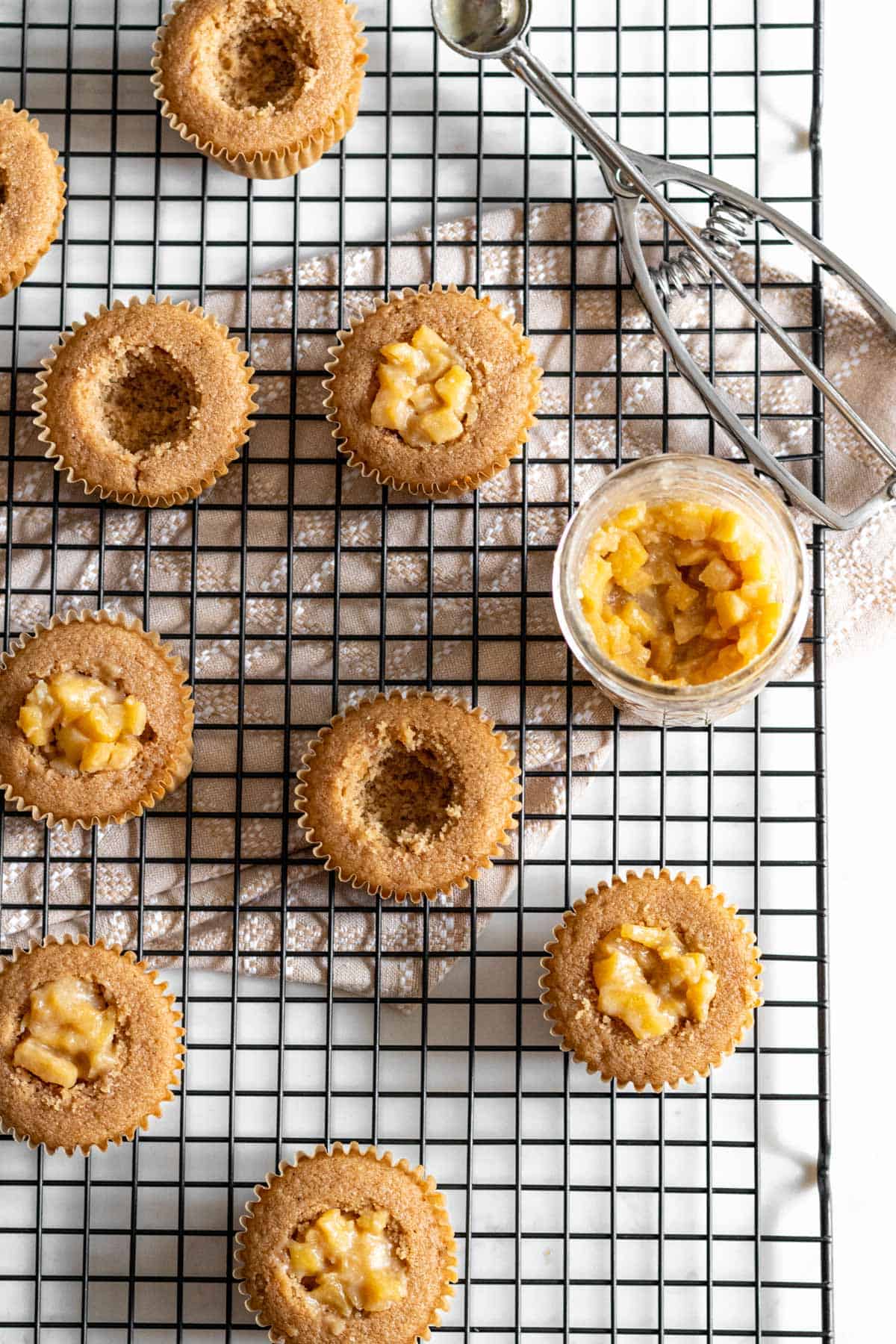 cupcakes on cooling rack with center of cake cut out and apple pie filling in half the cupcakes