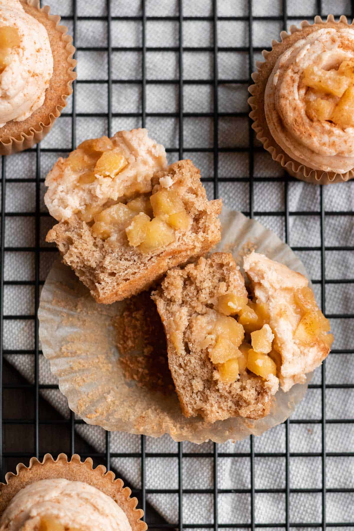 apple pie cupcake cut in half with apple pie filling in center and frosting and apple pie filling on top