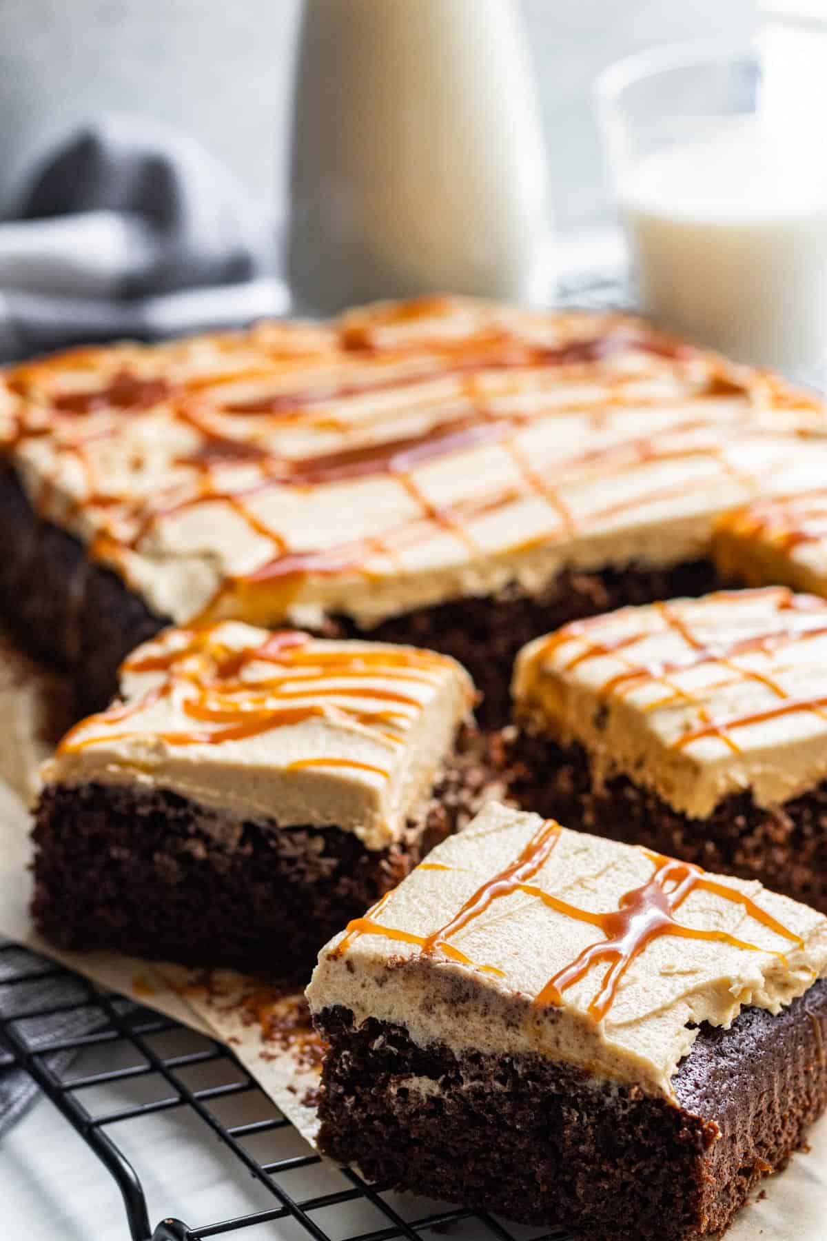 slices of chocolate sheet cake with salted caramel frosting drizzled with salted caramel with milk in glass 