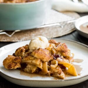 plate of apple crisp with blue baking dish of apple crisp in background