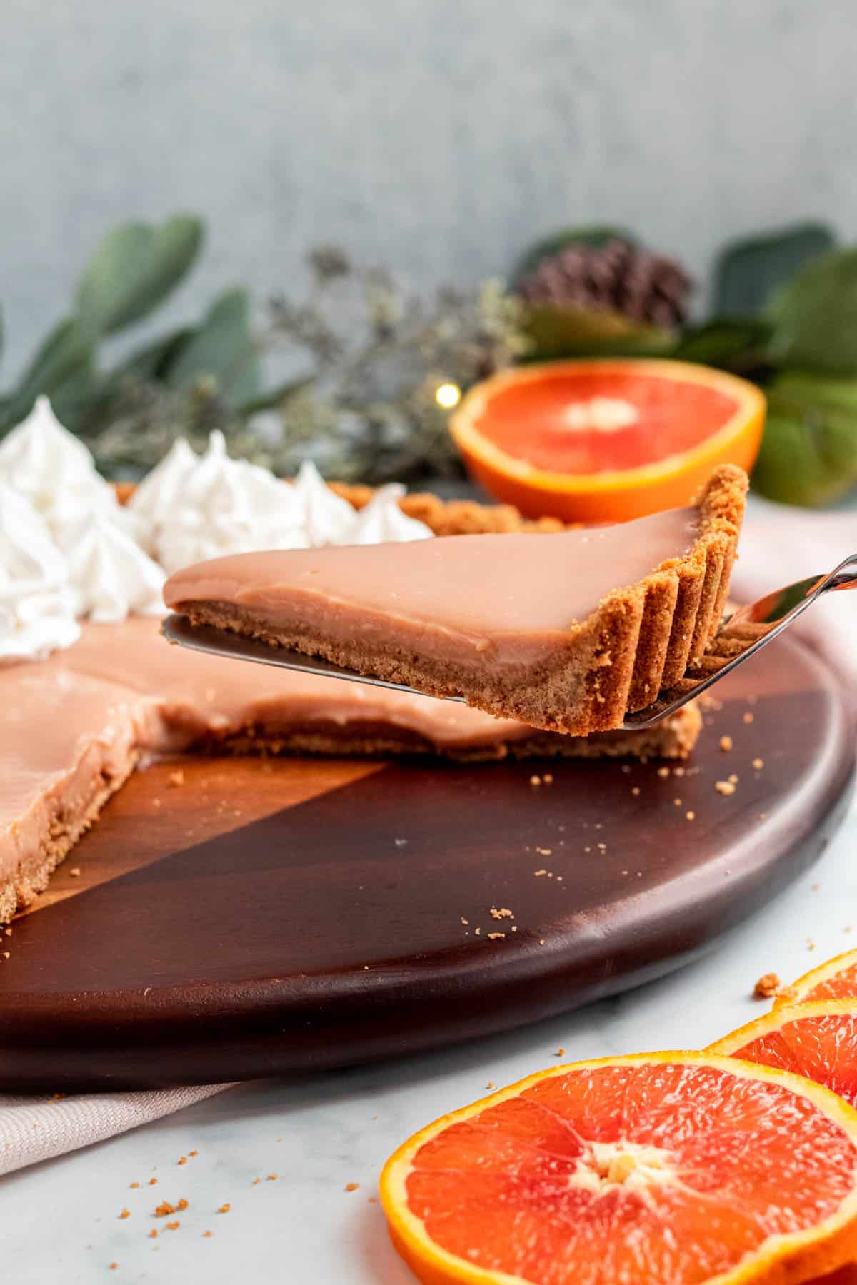 a slice of blood orange tart is being lifting from the whole tart on a serving spatula