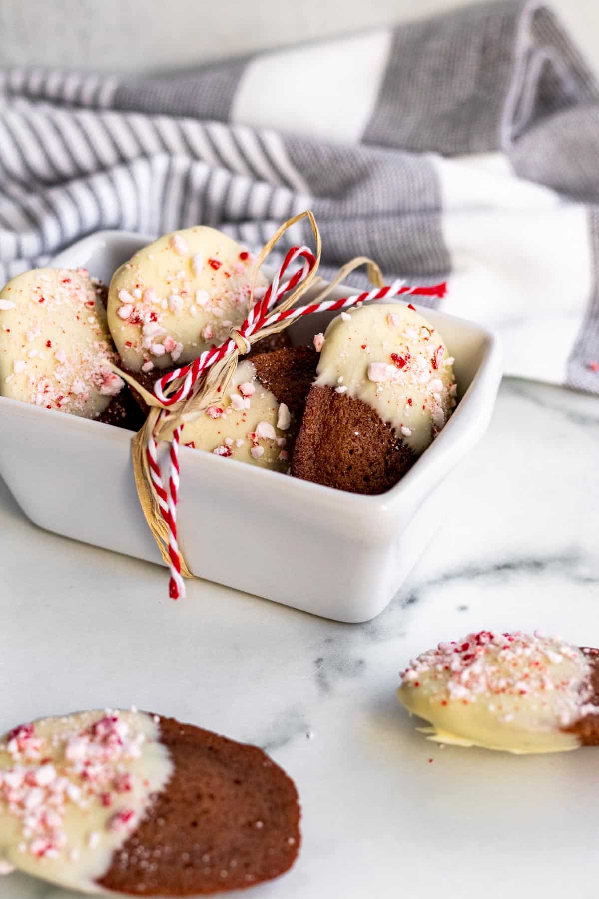 white mini ceramic bread pan with chocolate madeleines dipped in white chocolate and peppermint candies