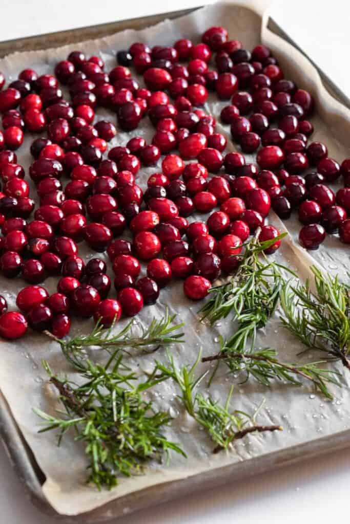 cranberries and rosemary on a parchment lined baking tray