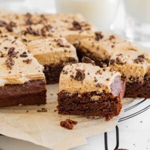 brownies with espresso frosting on top of a cooling rack with glasses of milk in background