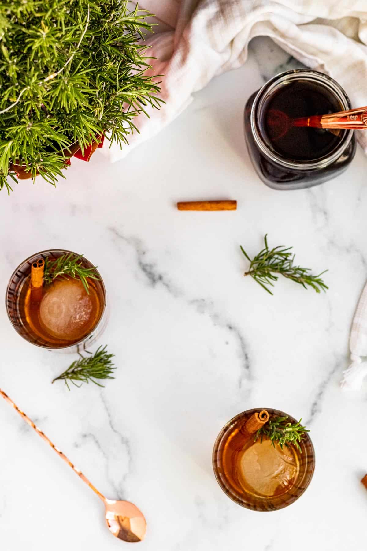 overhead view of 2 bourbon cocktails with sprigs of rosemary and cinnamon sticks for garnish