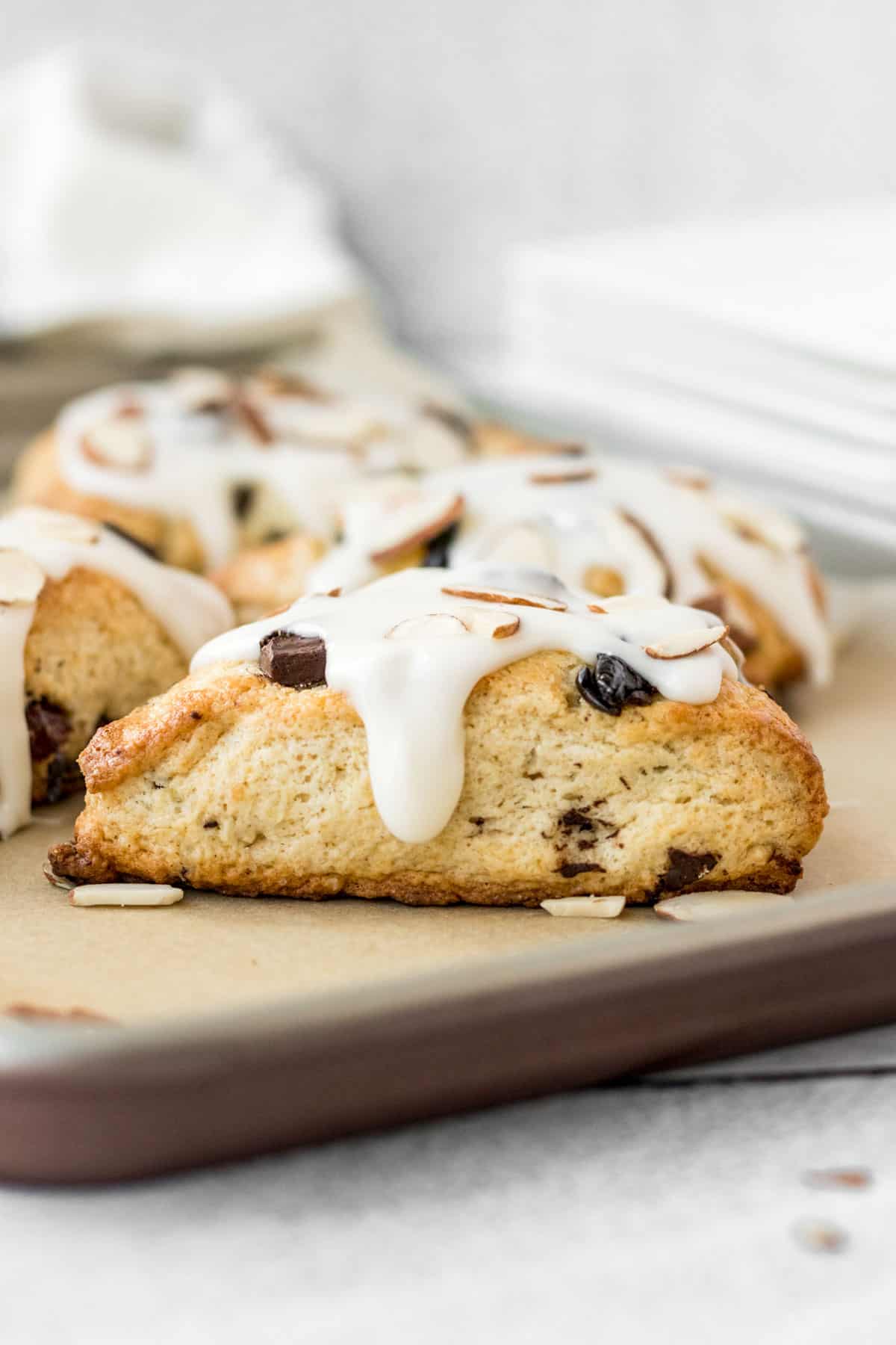 chocolate cherry almond scone with almond glaze one a baking sheet