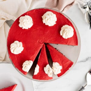 red velvet no-bake cheesecake with 2 slices cut and another slice on a white plate