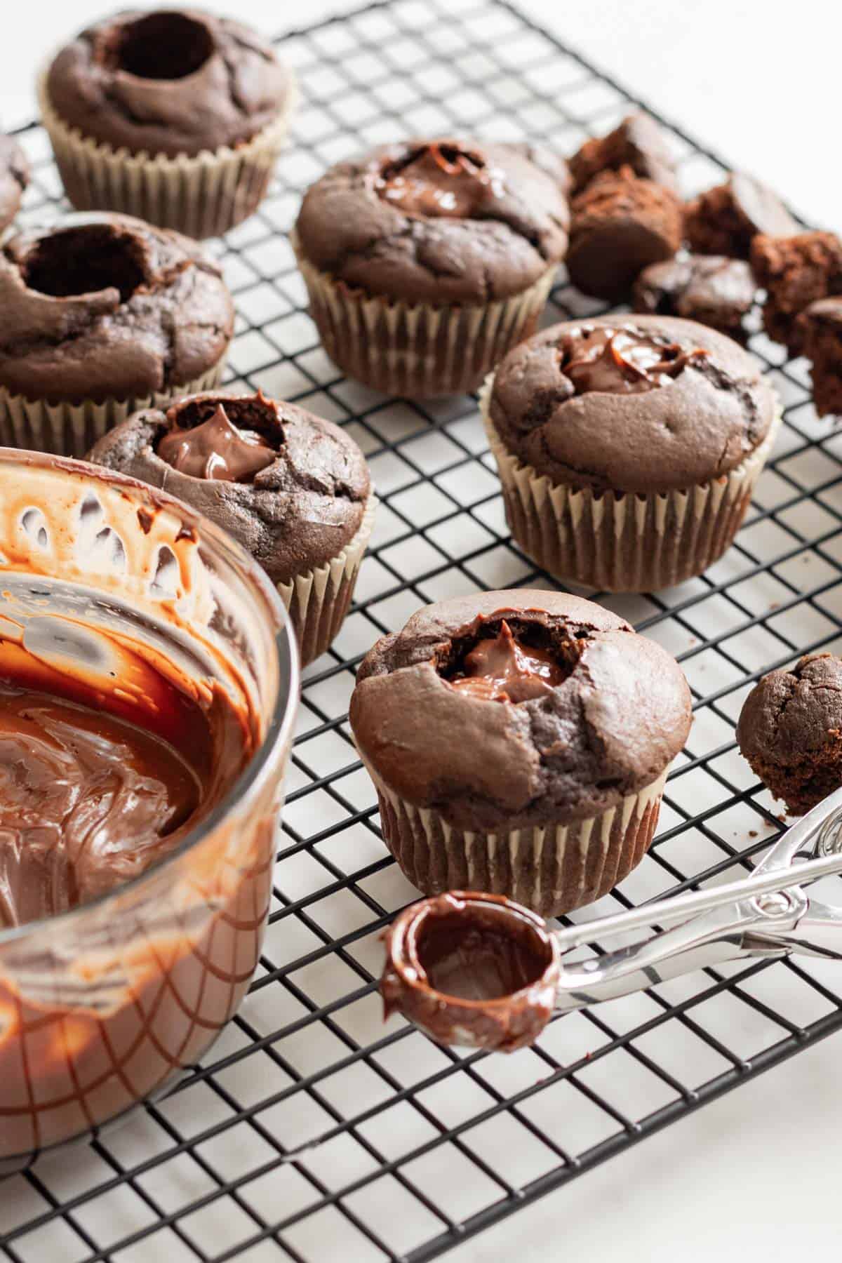 chocolate cupcakes with chocolate filling sitting on a cooling rack