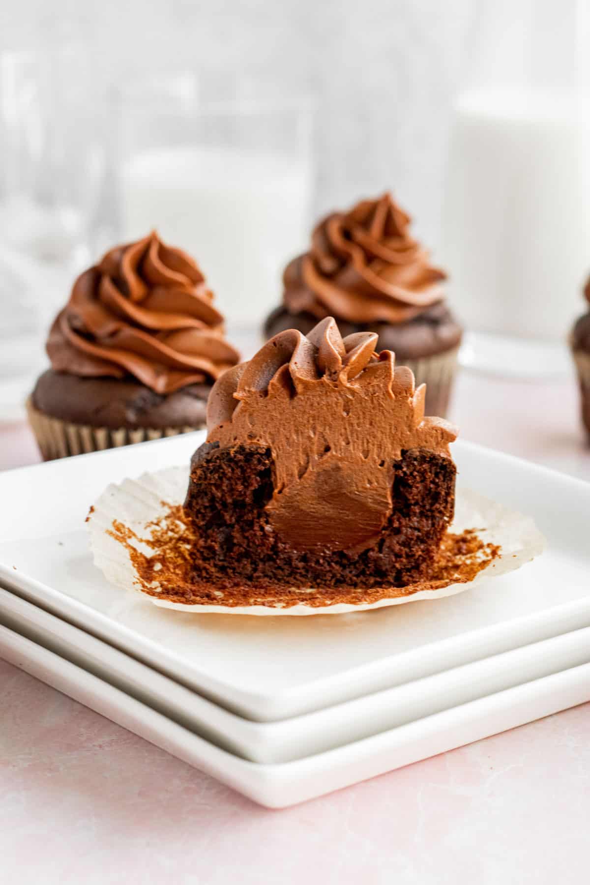 triple chocolate cupcake cut in half showing chocolate filling sitting on a stack of white plates