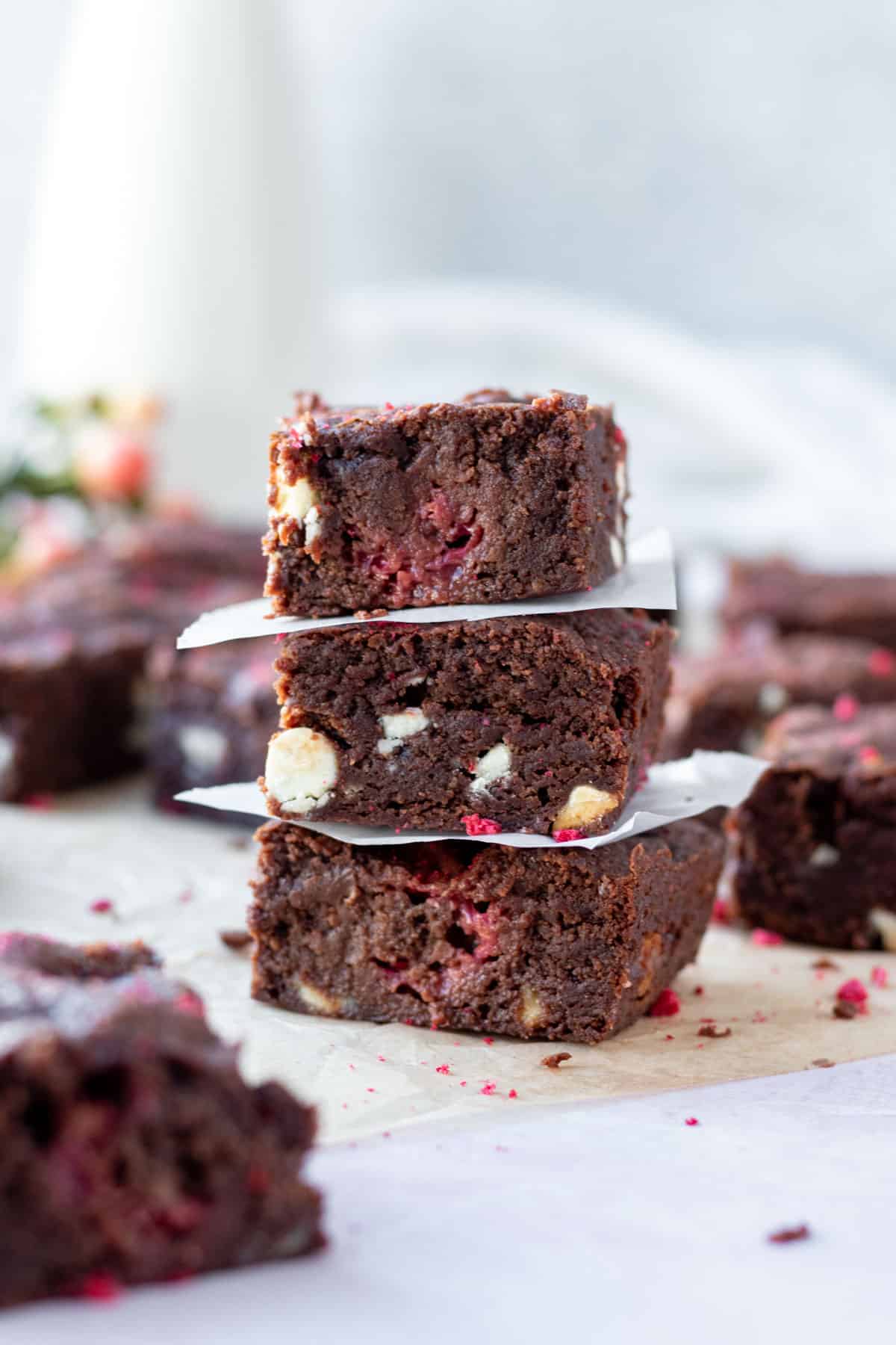 stack of three white chocolate and raspberry brownies with more brownies in the background