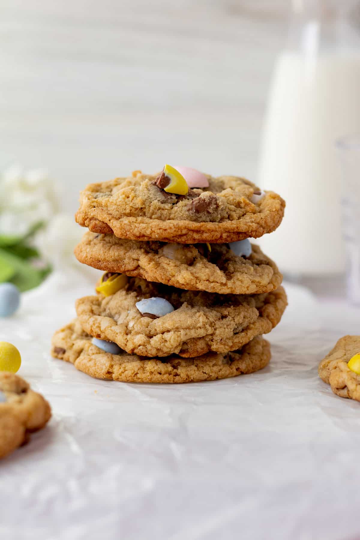 stack of mini egg cookies with glass pitcher of milk in background