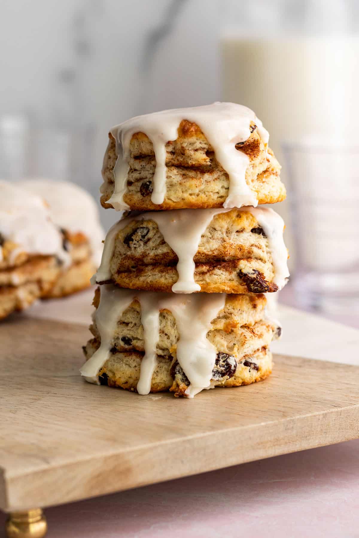 stack of cinnamon raisin biscuits with vanilla glaze with glass of milk in background