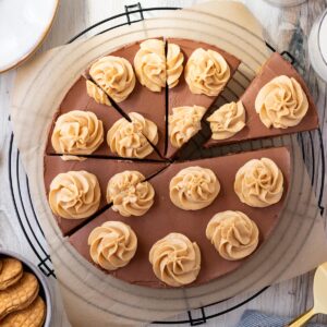 chocolate peanut butter cheesecake on top of a black wire cooling rack with a bowl of peanut butter cookies next to it