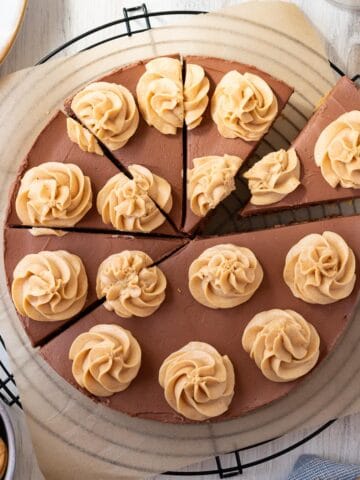 chocolate peanut butter cheesecake on top of a black wire cooling rack with a bowl of peanut butter cookies next to it