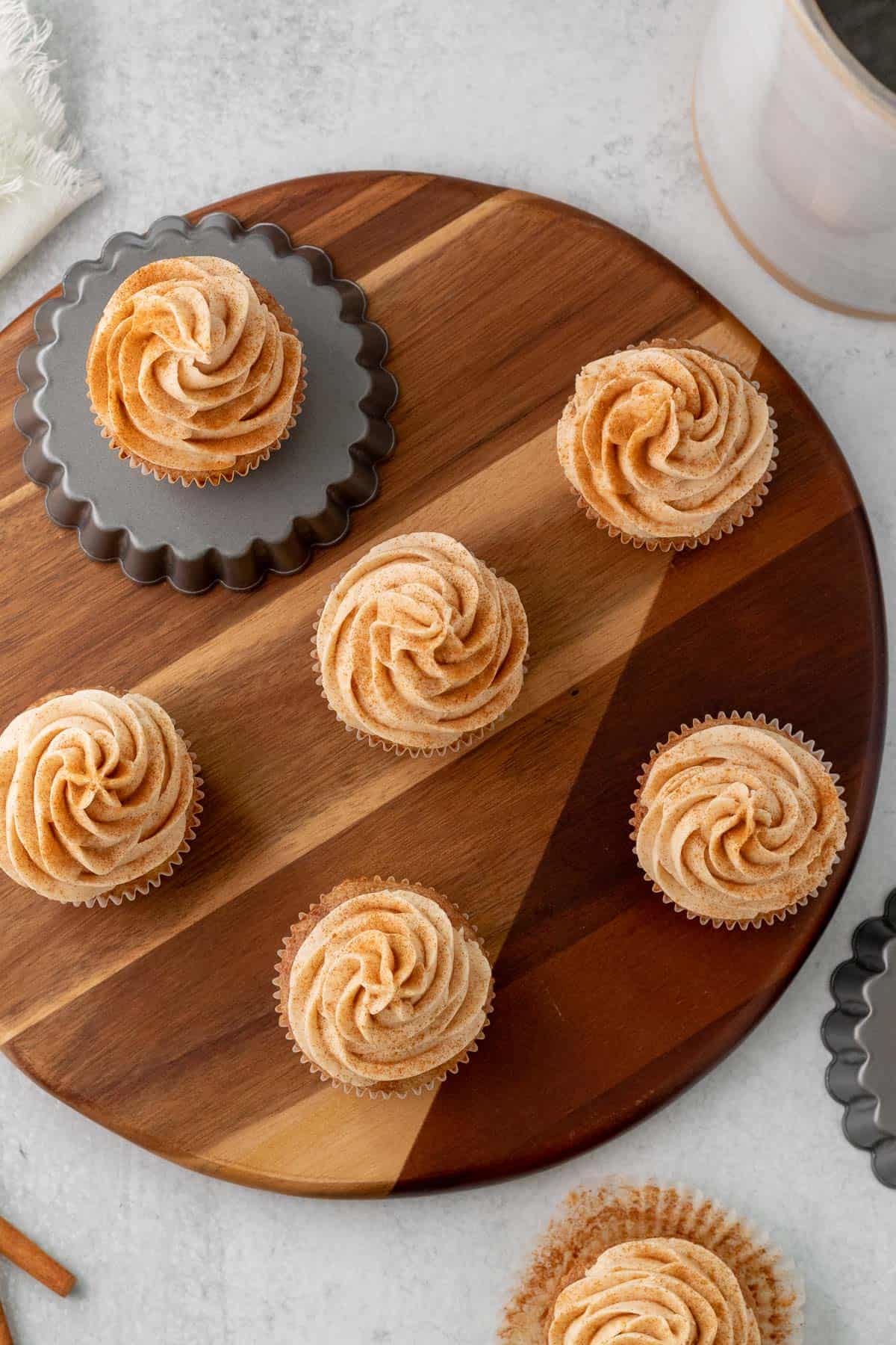 cinnamon cupcakes sitting on a round wood board