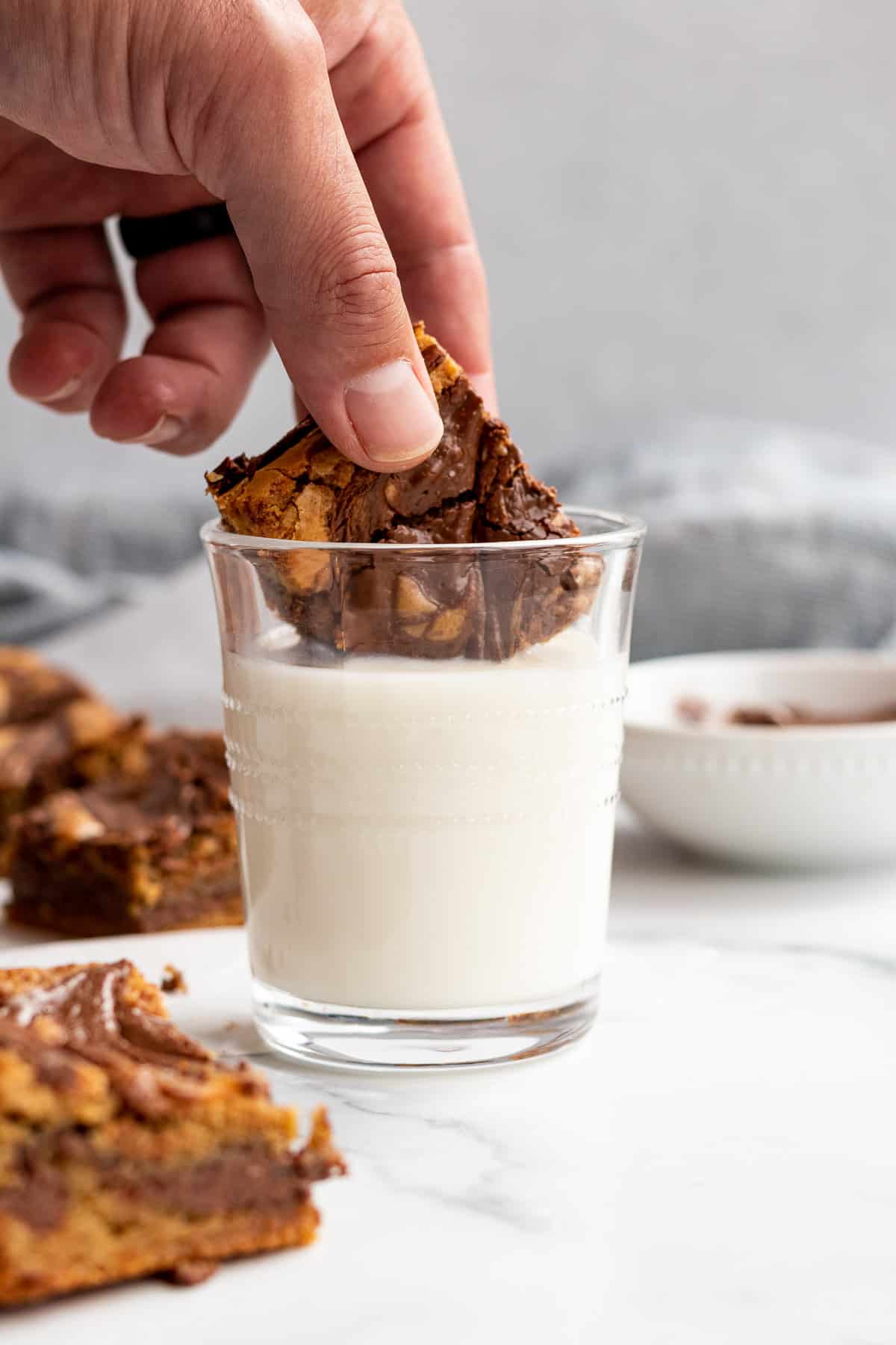 nutella blondie being dipped into a glass of milk