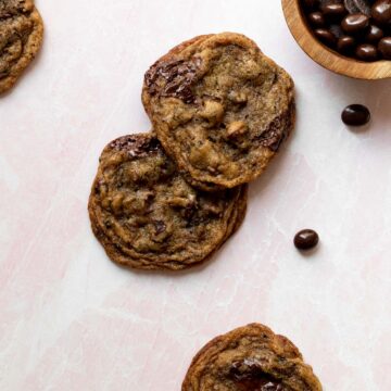 espresso chocolate chip cookies on a pink background with a small bowl of chocolate espresso beans