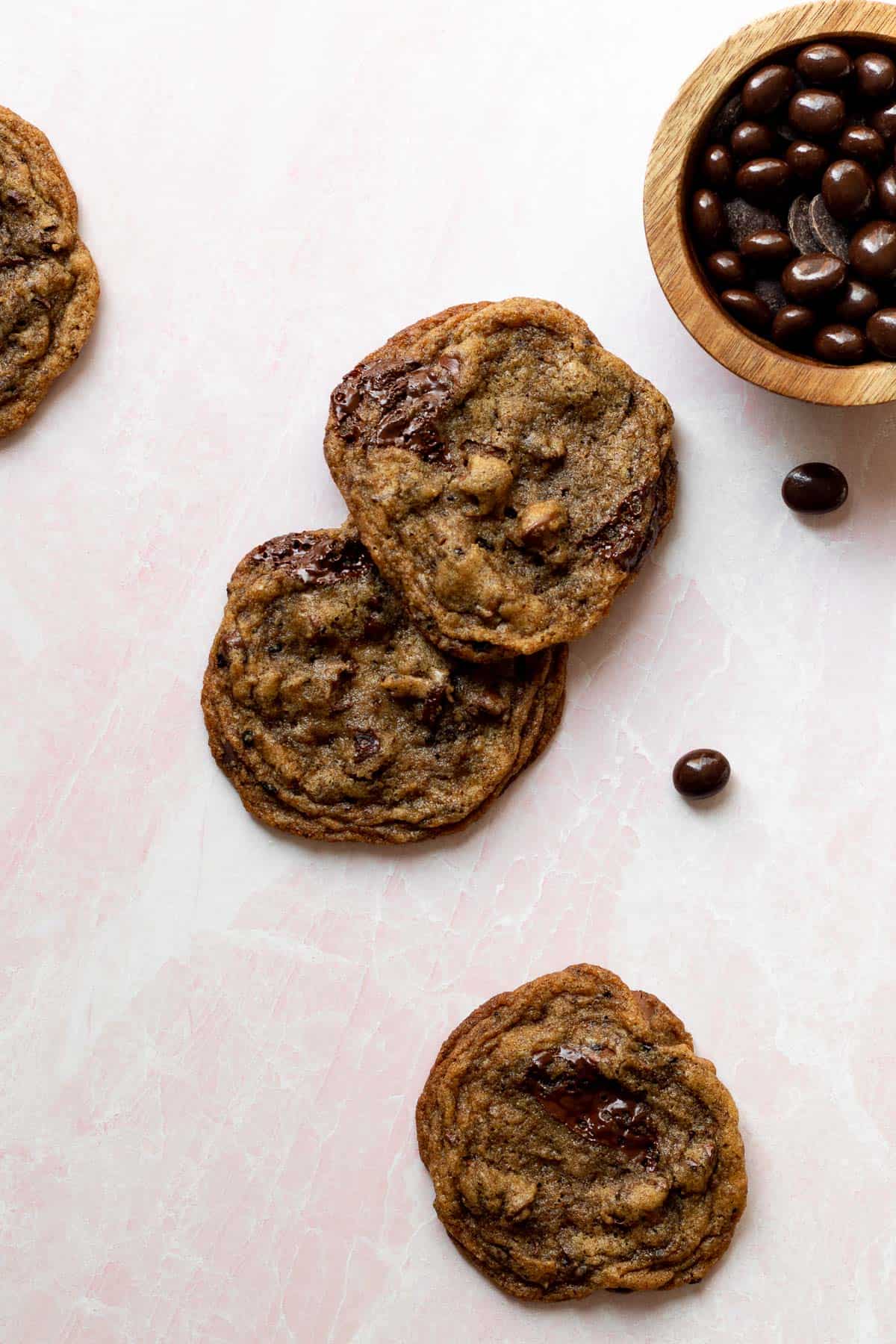 espresso chocolate chip cookies on a pink background with a small bowl of chocolate espresso beans