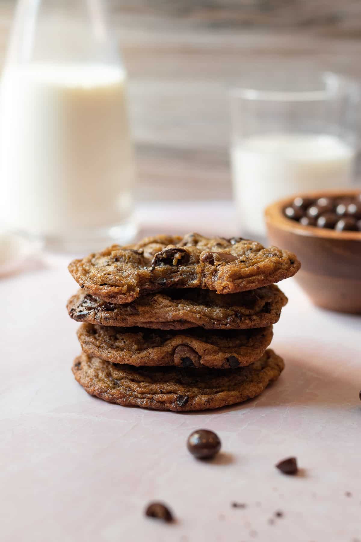 stack of espresso chocolate chip cookies with glasses of milk in the background